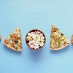 Assortiment de junk food illustrant les envies incontrôlées : pizza, pâtisseries sucrées et pop-corn colorés