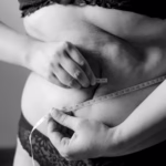 Femme tirant sur un ruban autour de son ventre – perdre la graisse du ventre naturellement
