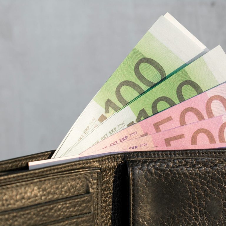 un portefeuille rempli de billet qui montre le bien-être financier