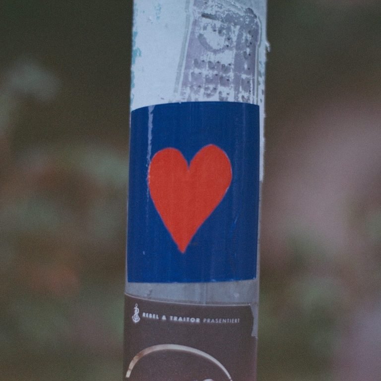 Autocollant avec un cœur rouge sur fond bleu symbolisant le sevrage naturel et la bienveillance envers soi