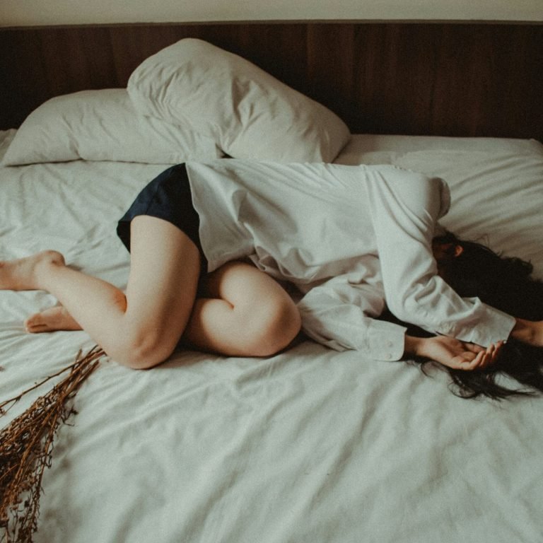 Femme fatiguée allongée sur un lit, illustrant la fatigue chronique et le besoin d'une pause.